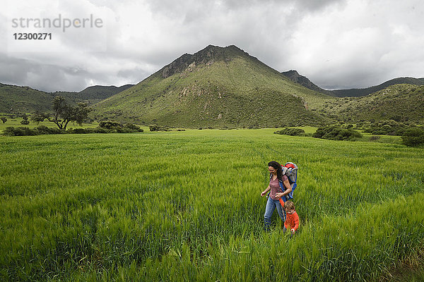 Mutter mit Sohn beim Wandern durch ein Feld im archäologischen Gebiet von Xihuingo  Tepeapulco  Hidalgo  Mexiko