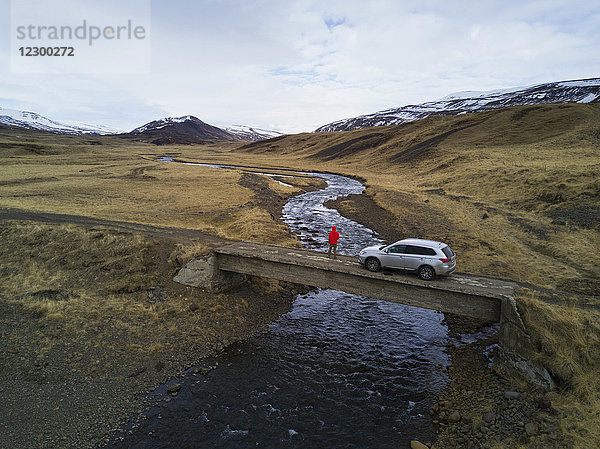 Abenteuerlicher Blick auf die Landschaft der Westfjorde von einer Brücke mit einem SUV in Island