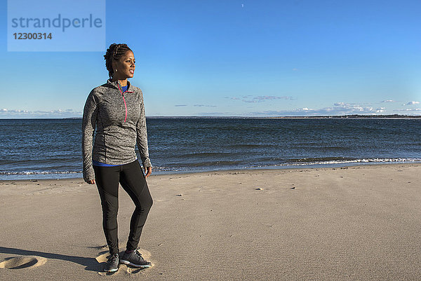Junge Frau steht an einem sonnigen Tag am Sandstrand  Newburyport  Massachusetts  USA