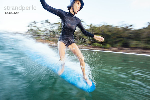 Eine Frau surft auf einem Longboard auf einer Welle am First Point in Noosa Heads.