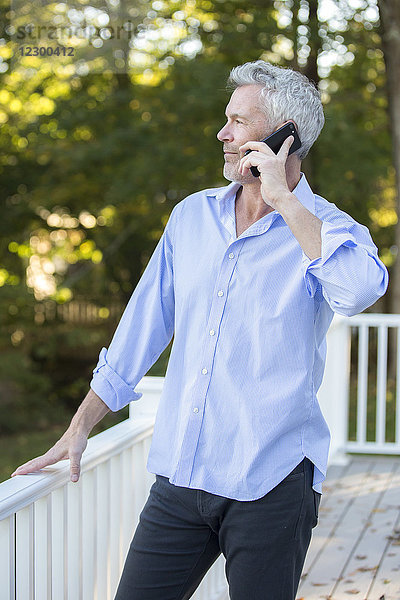 Grauhaariger Mann telefoniert auf einer Veranda im Freien  Orleans  Massachusetts  USA