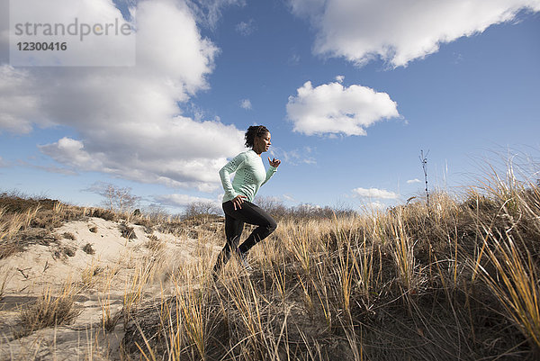 Junge Frau joggt bei sonnigem Wetter auf einem sandigen Weg  Newburyport  Massachusetts  USA
