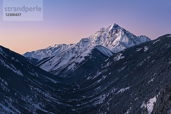 Ein bewaldetes Bergtal und der schneebedeckte Pyramid Peak bei stimmungsvoller violetter Morgendämmerung  Aspen  Colorado