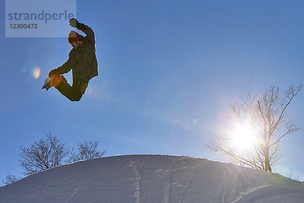 Snowboarder bei der Ausführung eines Air-Grab-Tricks in der Luft  Vermont  USA