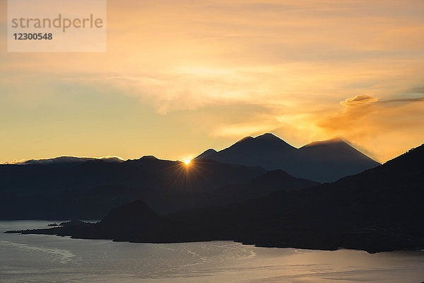 Landschaft mit Sonnenaufgang über dem Atitlan-See mit Silhouetten von Bergen  Guatemala