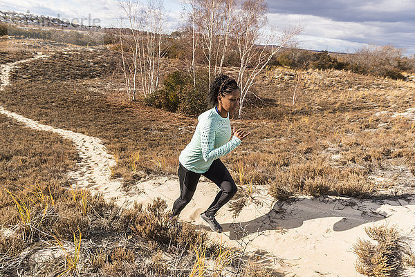 Junge Frau joggt auf schmalem Sandweg an einem sonnigen Tag  Newburyport  Massachusetts  USA