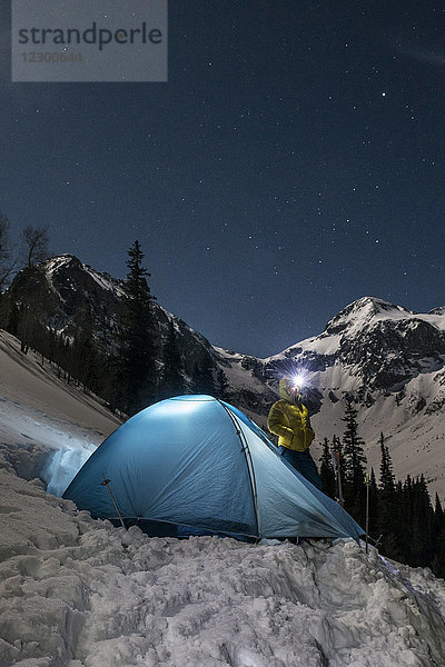Frau mit Stirnlampe beim Zelten in den schneebedeckten Bergen bei Nacht  Silverton  Colorado  USA