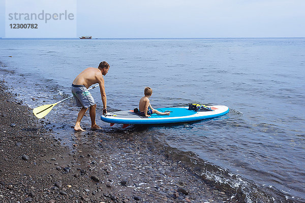 Vater und Sohn auf einem Surfbrett  Bali  Indonesien.