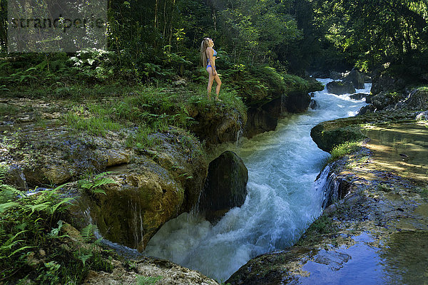 Seitenansicht einer Frau im Bikini am Flussufer im Dschungel von Semuc Champey  Guatemala