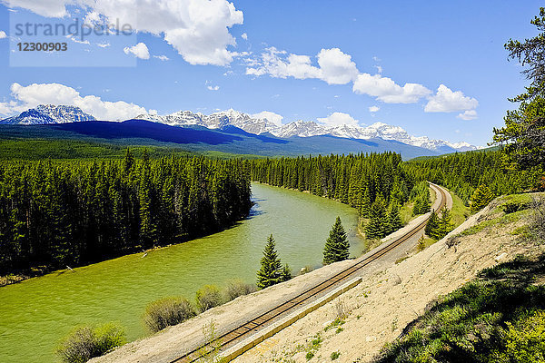 Eisenbahnlinie entlang des Flusses mit den kanadischen Rocky Mountains und Wald im Hintergrund  Banff National Park  Kanada