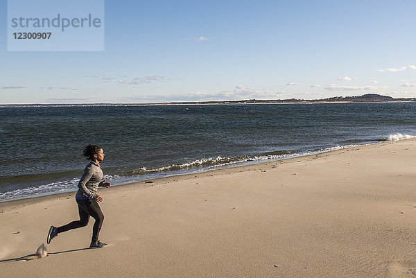 Junge Frau joggt am Sandstrand entlang der Meeresküste  Newburyport  Massachusetts  USA