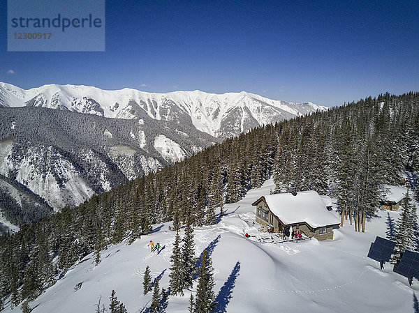 Luftaufnahme eines Skifahrerpaares beim Abstieg von einer einsamen Hütte auf einem schneebedeckten Berg  Aspen  Colorado  USA
