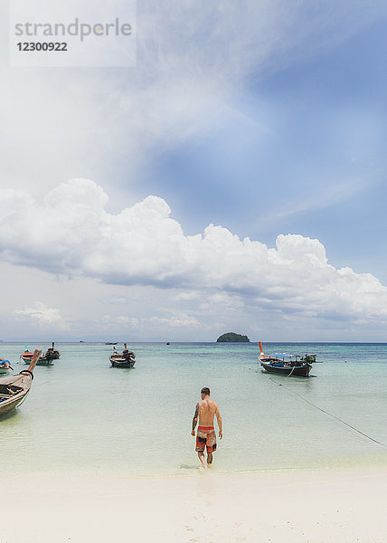 Ein Mann  der an einem thailändischen Strand ins Wasser geht