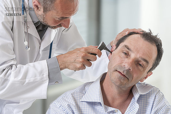Arzt bei der Untersuchung des Ohrs eines Patienten.