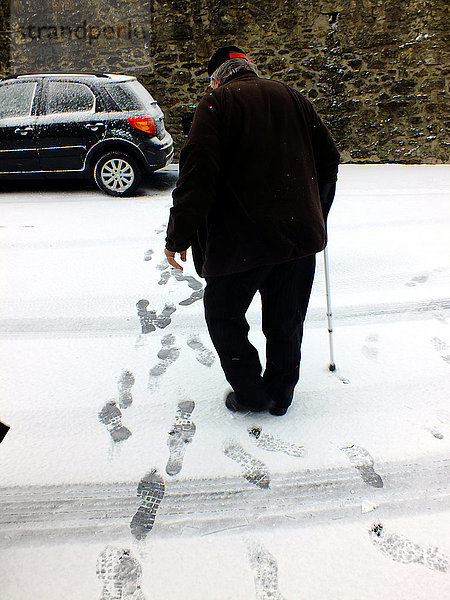 Ein älterer Mann geht durch den Schnee.
