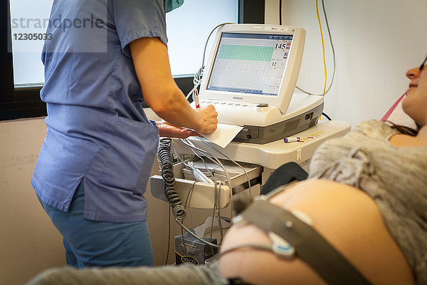 Reportage in der Notaufnahme für Entbindungen  Gynäkologie und Geburtshilfe im Krankenhaus Métropole  Chambéry  Frankreich. Eine Hebamme überwacht den Fötus einer Frau  die in der 40. Woche schwanger ist und die Bewegungen ihres Babys nicht mehr so stark spürt wie am Vortag.