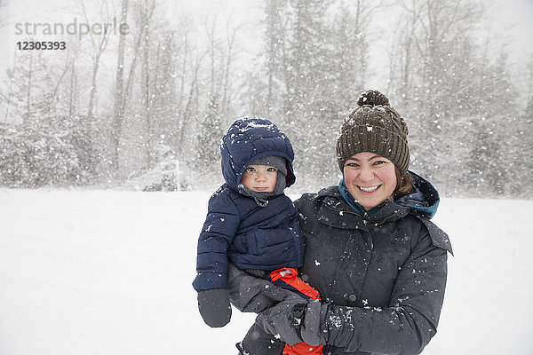 Winterporträt einer Mutter mit ihrem kleinen Sohn in warmer Kleidung
