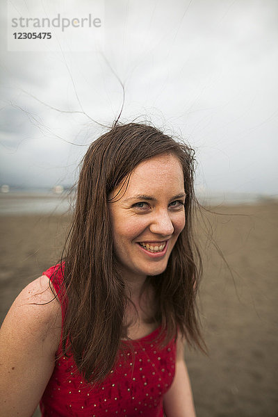 Kopf und Schultern Porträt der lächelnden Frau in rotem Tank-Top am Strand