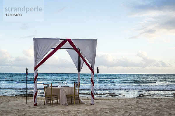 Ausgefallener Tisch mit Markise am Strand für ein romantisches Abendessen am Meer  Puerto Morelos  Halbinsel Yucatan  Mexiko