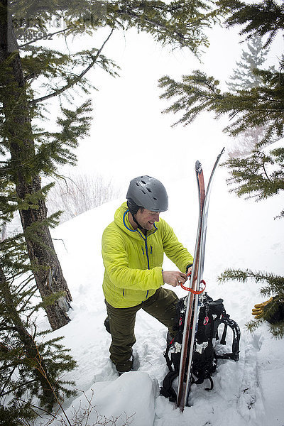 Skitourengeher schnallt Skier auf den Rucksack