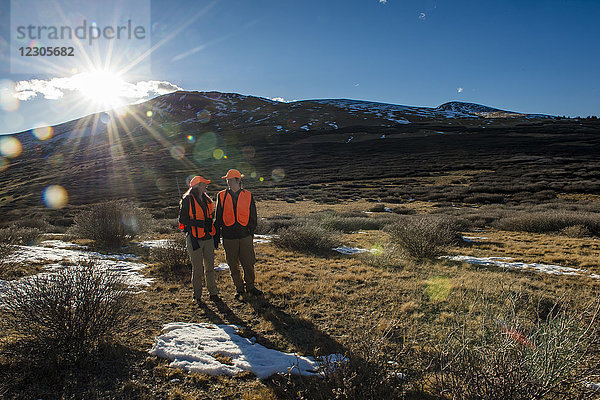 Großaufnahme eines Jägers und einer Jägerin in natürlicher Umgebung mit Bergen im Hintergrund