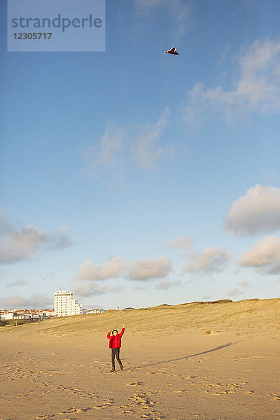 Entfernte Aufnahme eines Jungen  der am Strand mit einem Drachen spielt