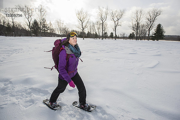 Frau mit Skibrille und Jacke beim Schneeschuhlaufen im Freien im Winter