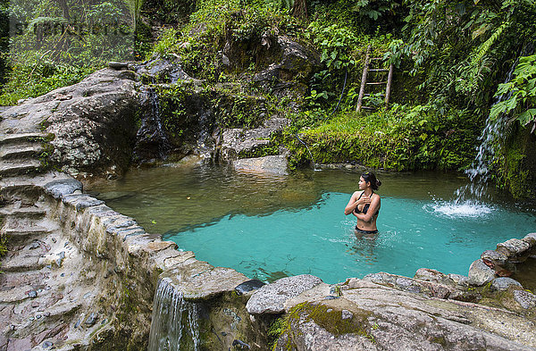 Taillenaufnahme einer Frau im Bikini beim Baden in einer Süßwasserquelle im Dschungel von Mindo  Provinz Pichincha  Ecuador