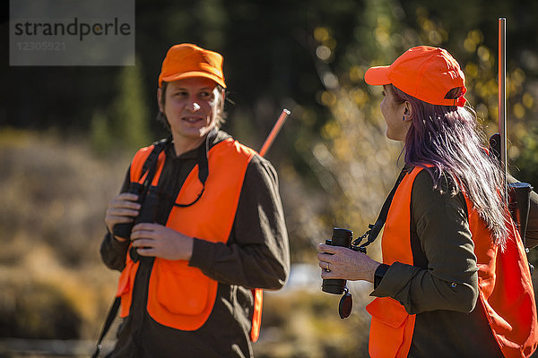 Männliche und weibliche Jäger unterhalten sich im Freien mit Ferngläsern in der Hand  Colorado  USA
