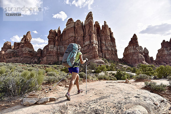 Wanderin  die gegen die Needles-Felsformation im Canyonlands-Nationalpark  Moab  Utah  USA  läuft