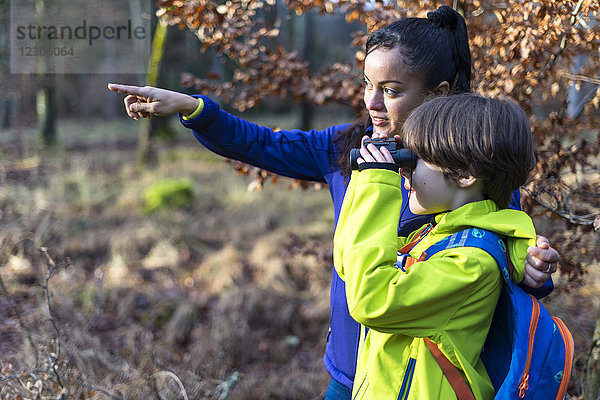 Seitenansicht von Mutter und Sohn  die im Wald durch ein Fernglas schauen