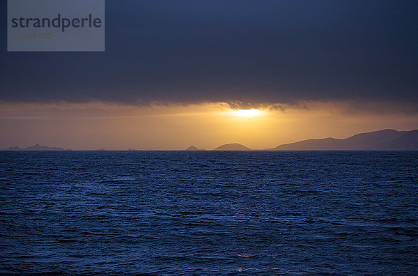 Meer bei bewölktem Sonnenuntergang mit Silhouetten von Küstenhügeln im Hintergrund  Porticcio  Korsika  Frankreich
