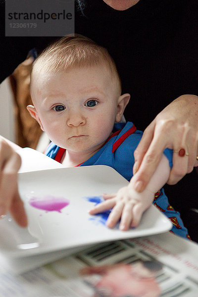 Mutter hilft Baby beim Malen Kunst tropft Farbe auf Papier  Kerroch  Bretagne  Frankreich