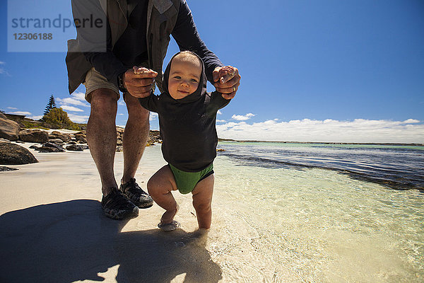 Vorderansicht des Großvaters  der mit einem kleinen Jungen am Strand spielt