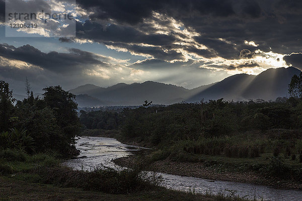 Sonnenlicht durchdringt die Wolken über einem schmalen Bergfluss in der Abenddämmerung  Pai  Mae Hong Soon  Thailand