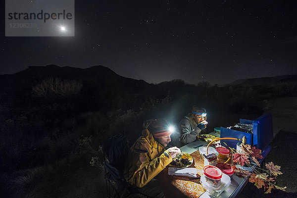 Junges Paar isst Thanksgiving-Abendessen beim Zelten im Zion-Nationalpark bei Nacht  Utah  USA