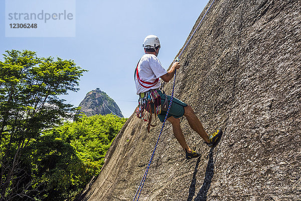 Seitenansicht eines abenteuerlustigen Mannes beim Klettern am Morro da Urca neben dem Zuckerhut  Rio de Janeiro  Brasilien