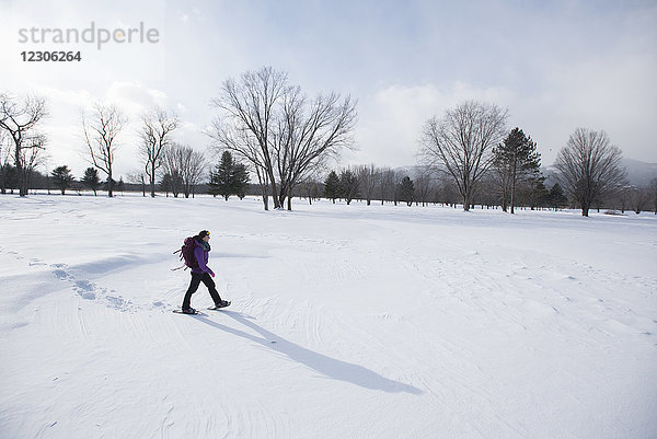 Seitenansicht einer einzelnen Frau beim Schneeschuhwandern im Freien im Winter