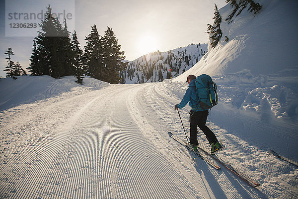Rückansicht eines Mannes beim Skilanglauf auf einer verschneiten Straße  North Cascades National Park  Washington State  USA