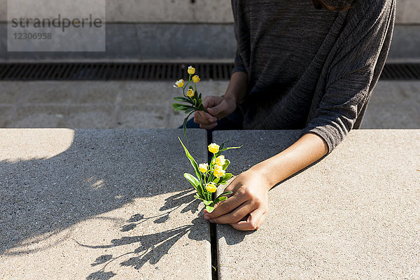 Nahaufnahme einer Frau mit gelber Blume auf Beton