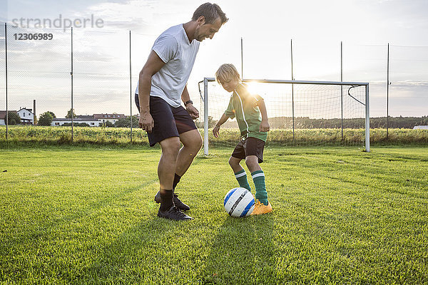 Trainer und junger Fußballspieler auf dem Fußballplatz bei Sonnenuntergang