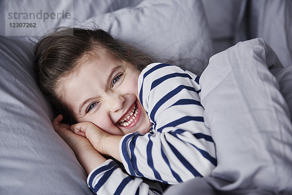 Porträt des lachenden Mädchens im Bett liegend