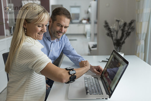 Mann und lächelnde Frau mit tragbarem Arm am Schreibtisch