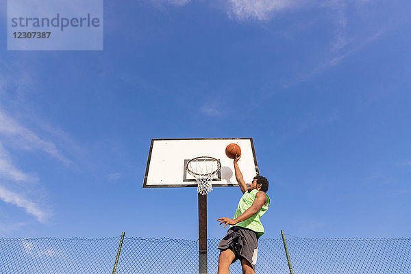 Junger Mann spielt Basketball