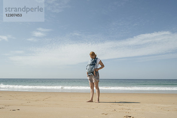 Spanien  Cape Trafalgar  Mutter mit Baby im Tragesitz am Strand