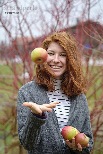 Porträt eines rothaarigen Teenagermädchens mit vier Äpfeln