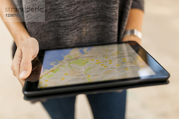 Nahaufnahme einer Frau  die ein Tablett mit digitaler Straßenkarte hält