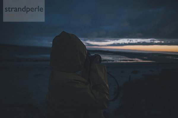Frankreich  Bretagne  Landeda  Dunes de Sainte-Marguerite  Frau an der Küste beim Fotografieren am Abend