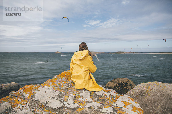 Frankreich  Bretagne  Landeda  Dunes de Sainte-Marguerite  junge Frau auf Felsen an der Küste sitzend