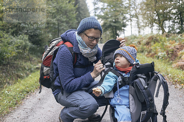 Sohn isst Brot  sitzt in seinem Rückenkorb  neben seiner Mutter während des Wanderns.